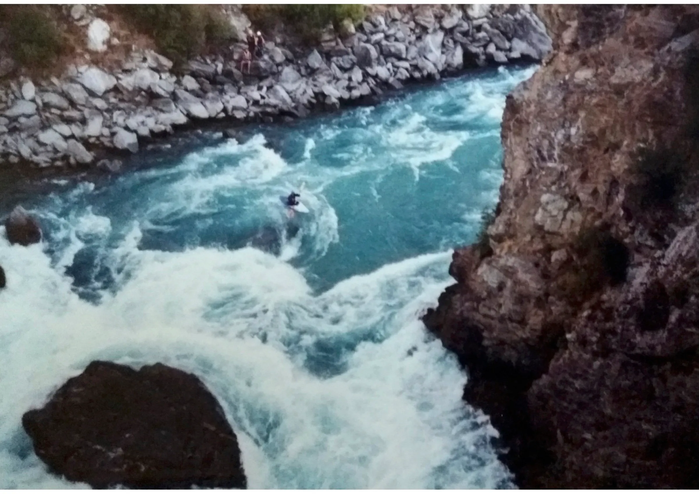 A kayaker in heavy whitewater in a rocky gorge