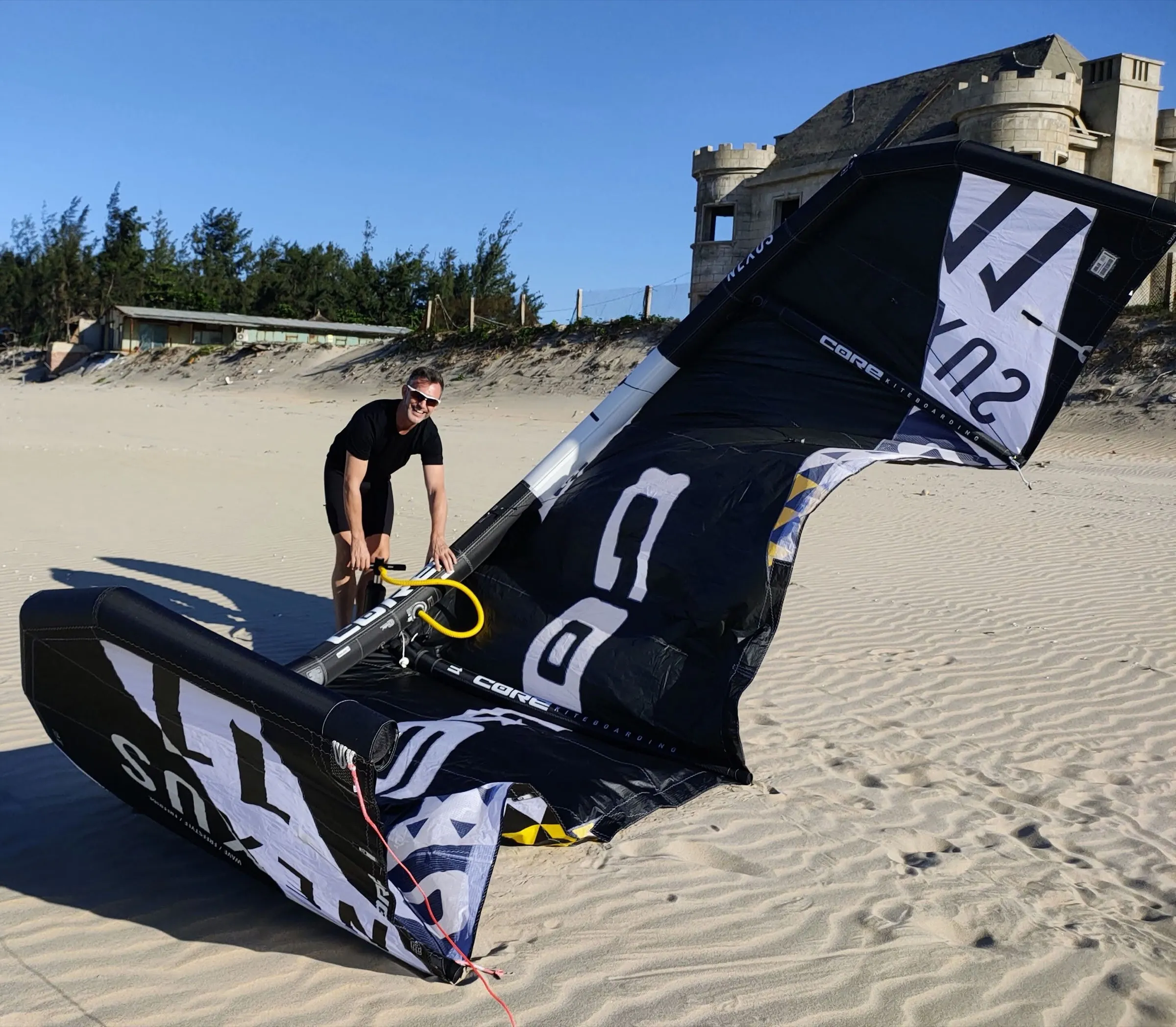 Andrew pumping up a kite on a sandy beach